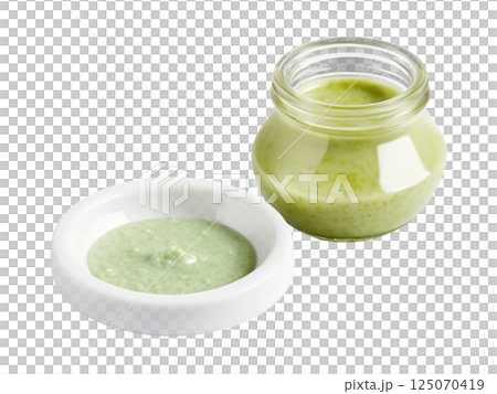Wasabi Sauce A spicy wasabi sauce in a clear glass jar, its pale green color evident. A small glass dish 125070419