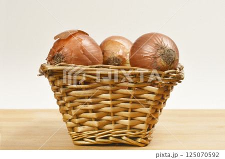 Basket filled with brown onions 125070592