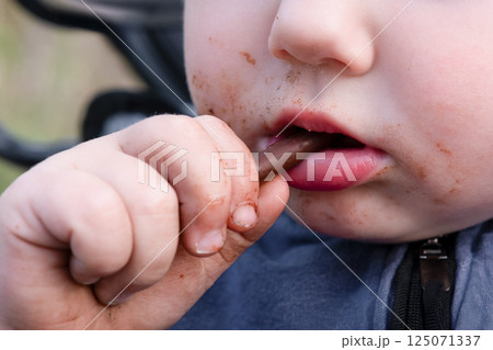 Little boy eating chocolate stick close up Little boy eating chocolate stick close up 125071337