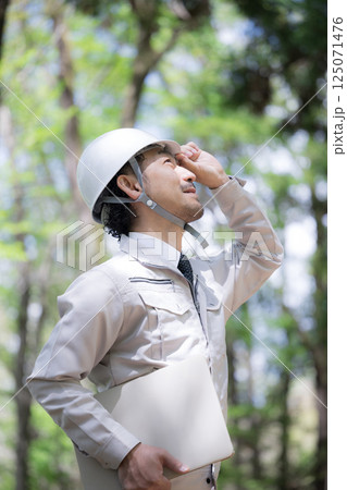 林業や森林整備で森の確認をするヘルメットの作業着の男性、施工管理など　横顔のクローズアップ 125071476