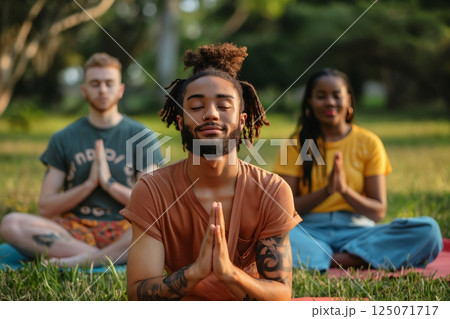 Group of young people meditating in lotus position during their yoga practice at the park 125071717