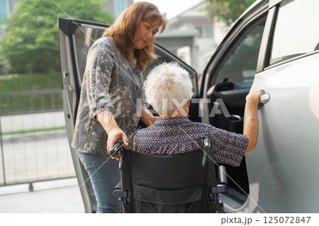 Caregiver help Asian elderly woman disability patient get in her car. 125072847