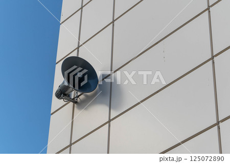Loudspeaker announcing on white building with blue sky background Loudspeaker announcing on white building with blue sky background 125072890