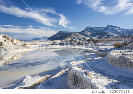 Salt industry extracting salt from brine in evaporation ponds with mountains reflecting on water surface in Utah, USA Salt industry extracting salt from brine in evaporation ponds with mountains reflecting on water surface in Utah, USA 125073181