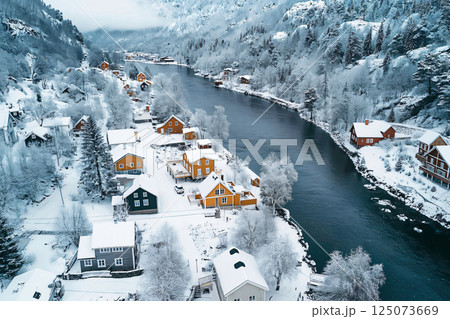 Drone capturing a birds eye view of a small Norwegian village nestled along a river in winter 125073669