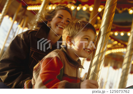 Mother and her son are laughing and having a good time riding a carousel at a vintage amusement park 125073762