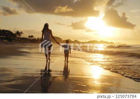 Mother and her son are enjoying a beautiful sunset while walking on the beach 125073784