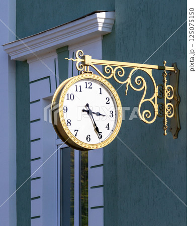 Big street clock hanging on a wall of stone building 125075150