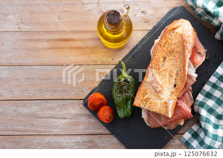 Spanish serrano ham sandwich on wooden table. Spanish bocadillo de jamon serrano. Spanish serrano ham sandwich on wooden table. Spanish bocadillo de jamon serrano. 125076632