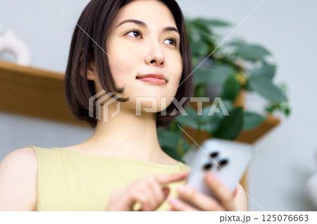 部屋でスマホを見る若い女性 部屋でスマホを見る若い女性 125076663