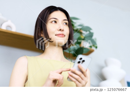 部屋でスマホを見る若い女性 部屋でスマホを見る若い女性 125076667