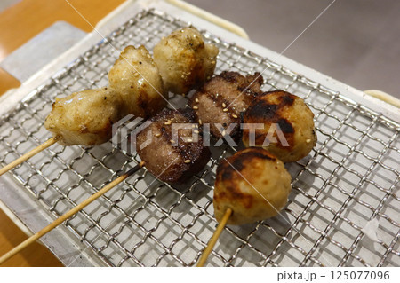 chicken meat, minced meat balls and beef ox tongues arranged on a wire mesh grill 125077096