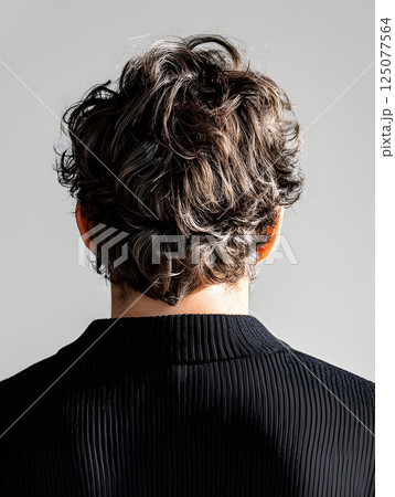 Young athletic guy standing in a T-shirt. Light background. View from behind. 125077564