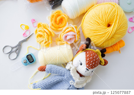 Crafting essentials. Yarn balls, crochet tools, and handmade toy 125077887