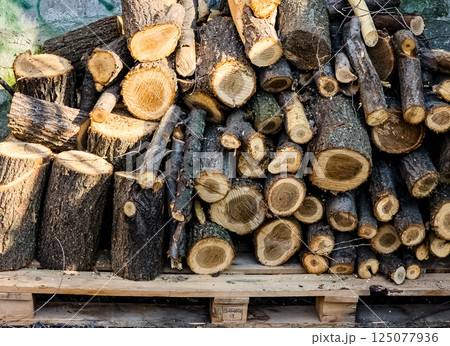 A small pile of firewood stacked on top of each other, firewood on a pallet. 125077936