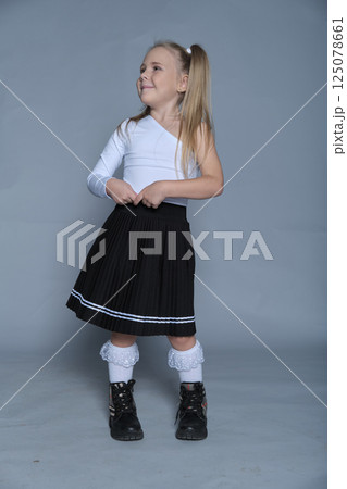 A confident young girl models a trendy black skirt and white top, perfect for children s fashion portfolios. A confident young girl models a trendy black skirt and white top, perfect for children s fashion portfolios. 125078661