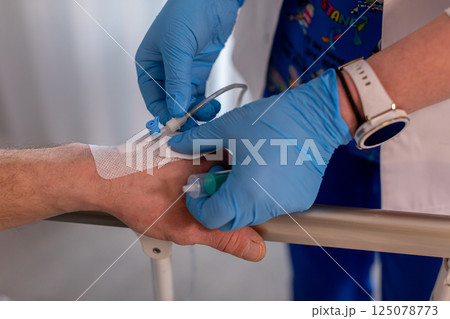 A dedicated nurse is attentively caring for a patient who has an intravenous line in the hospital 125078773
