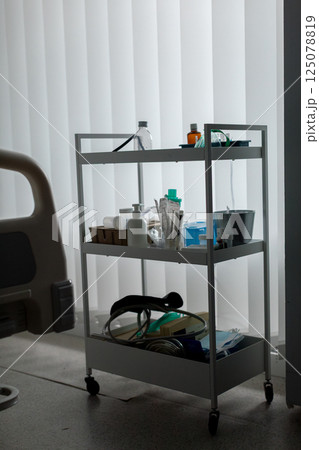 A Medical Utility Cart Equipped with Various Items Illuminated in Dim Lighting Conditions A Medical Utility Cart Equipped with Various Items Illuminated in Dim Lighting Conditions 125078819
