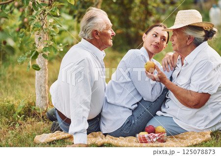 Sitting on the ground. Daughter is with her senior mother and father is in the garden Sitting on the ground. Daughter is with her senior mother and father is in the garden 125078873