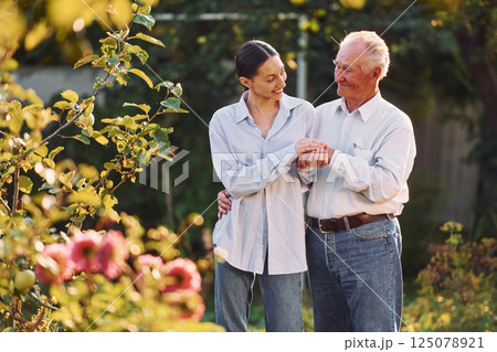 Conception of love. Embracing each other. Daughter is with her senior father in the garden at daytime Conception of love. Embracing each other. Daughter is with her senior father in the garden at daytime 125078921