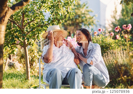 Sitting together. Young woman is with her senior mother is in the garden Sitting together. Young woman is with her senior mother is in the garden 125078936