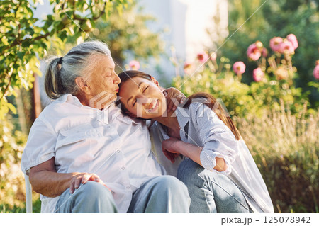 Sitting and embracing each other. Young woman is with her senior mother is in the garden 125078942