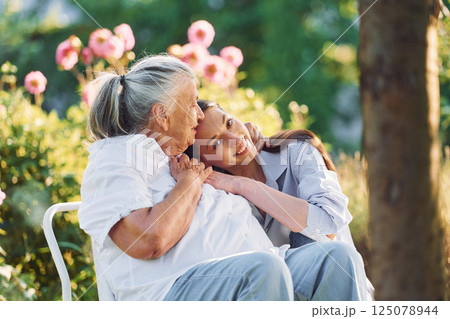 Sitting and embracing each other. Young woman is with her senior mother is in the garden 125078944
