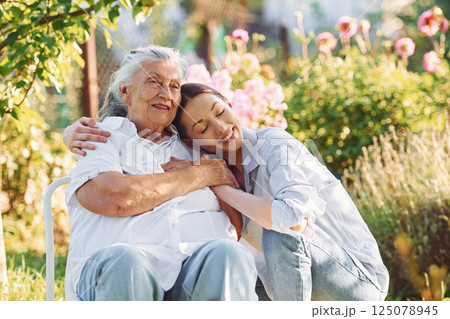 Sitting and embracing each other. Young woman is with her senior mother is in the garden 125078945