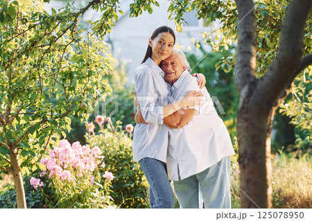 Time for a hugs. Young woman is with her senior mother is in the garden 125078950