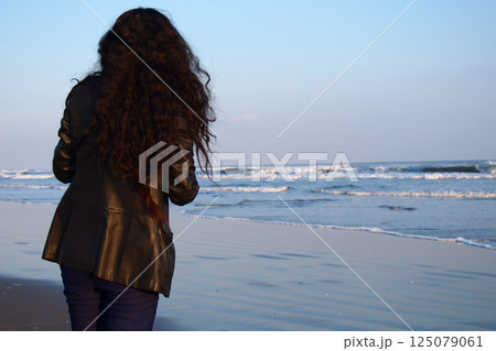 夕暮れの海を見つめる淋しげな女性 125079061