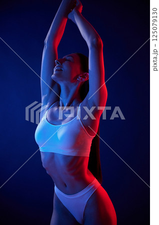 Beautiful colors. Young woman in underwear is in the studio with neon lights 125079130