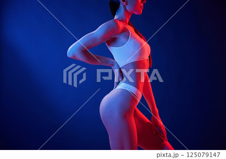 Blue and red colors. Young woman in underwear is in the studio with neon lights Blue and red colors. Young woman in underwear is in the studio with neon lights 125079147