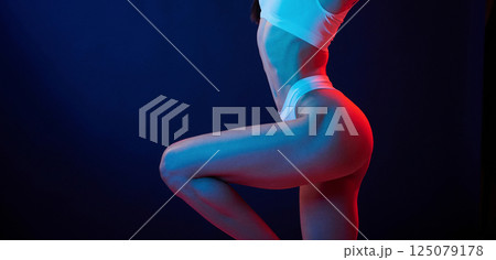 Beautiful slim body type. Young woman in underwear is in the studio with neon lights Beautiful slim body type. Young woman in underwear is in the studio with neon lights 125079178