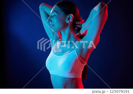 Feeling relaxed. Young woman in underwear is in the studio with neon lights Feeling relaxed. Young woman in underwear is in the studio with neon lights 125079191