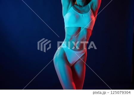 Tall and slender. Young woman in underwear is in the studio with neon lights 125079304