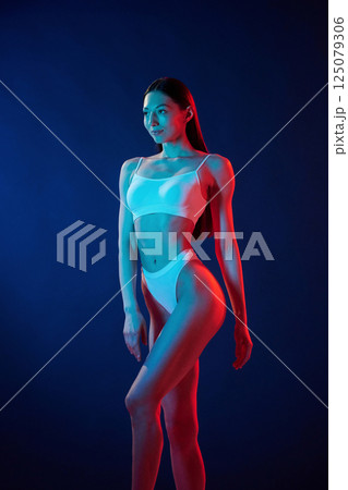 Tall and slender. Young woman in underwear is in the studio with neon lights 125079306