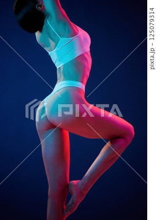 View from the side. Young woman in underwear is in the studio with neon lights 125079314