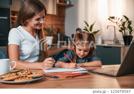Learning how to draw. Young mother with her daughter is together at apartment Learning how to draw. Young mother with her daughter is together at apartment 125079587