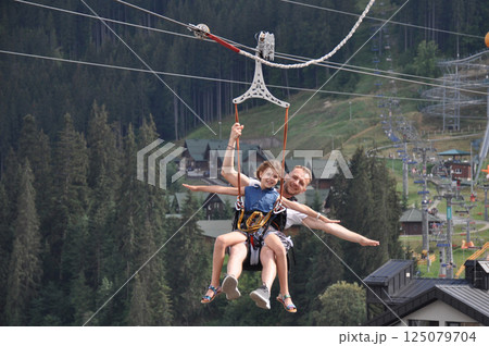 Happy father with his daughter is on the ski lift having fun and smiling. Majestic view of Carpathians 125079704