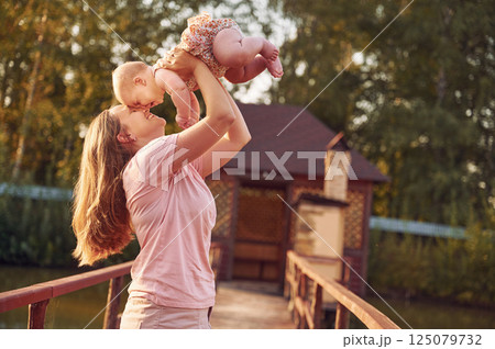 Holding baby in hands. Mother with her newborn son is outdoors on the lawn at the daytime Holding baby in hands. Mother with her newborn son is outdoors on the lawn at the daytime 125079732
