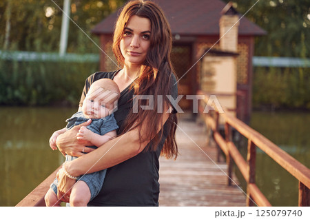 Mother with her newborn son is outdoors on the lawn at the daytime Mother with her newborn son is outdoors on the lawn at the daytime 125079740