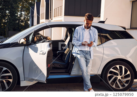 Young stylish man is with electric car at daytime 125079950