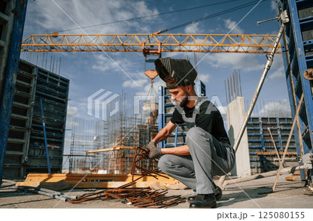 Working with rusty metal pieces. Man in uniform is on the construction site 125080155