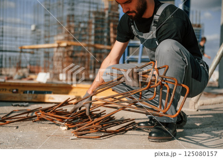 Working with rusty metal pieces. Man in uniform is on the construction site 125080157