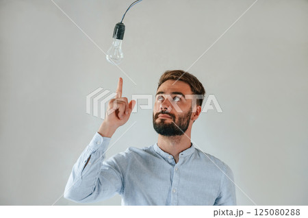 With light bulb in bright room. The man is making repairs in the apartment 125080288