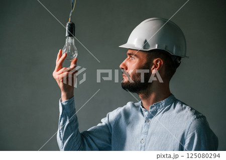Light bulb in the dark room. The man is making repairs in the apartment 125080294