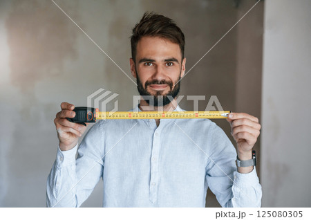 Holding ruler measurement tool. The man is making repairs in the apartment 125080305
