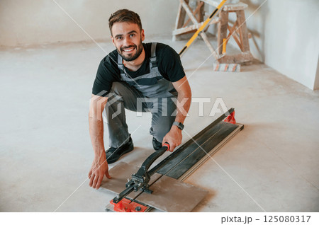 Tile cutting process. The man is making repairs in the apartment Tile cutting process. The man is making repairs in the apartment 125080317