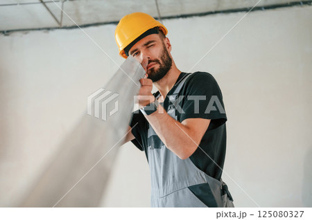 Holding construction material stuff by hands. The man is making repairs in the apartment 125080327