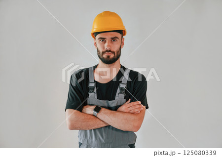 Standing in grey colored uniform. The man is making repairs in the apartment 125080339